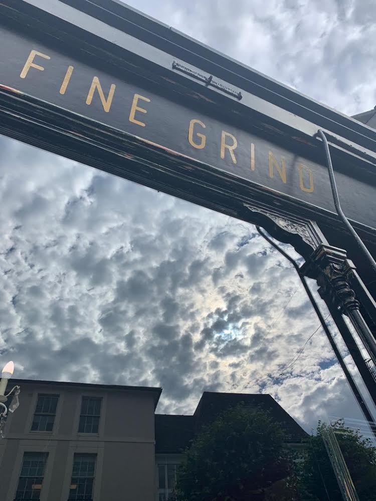 Fine Grind gold lettering on the Tunbridge Wells High Street shopfront against a cloudy sky
