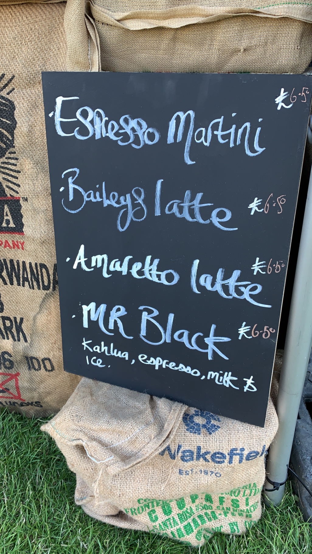 Chalkboard listing Espresso Martini, Baileys Latte, Amaretto Latte and Mr Black against hessian coffee sacks