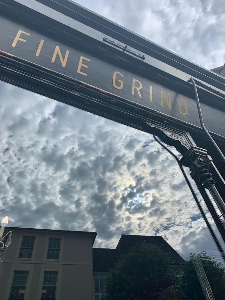 Fine Grind gold lettering on the Tunbridge Wells High Street shopfront against a cloudy sky
