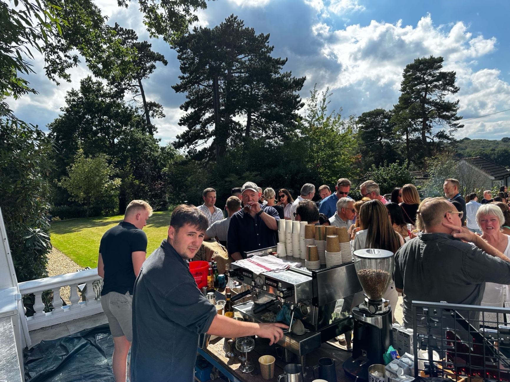 Crowd of guests being served coffee and cocktails at an exclusive private residence