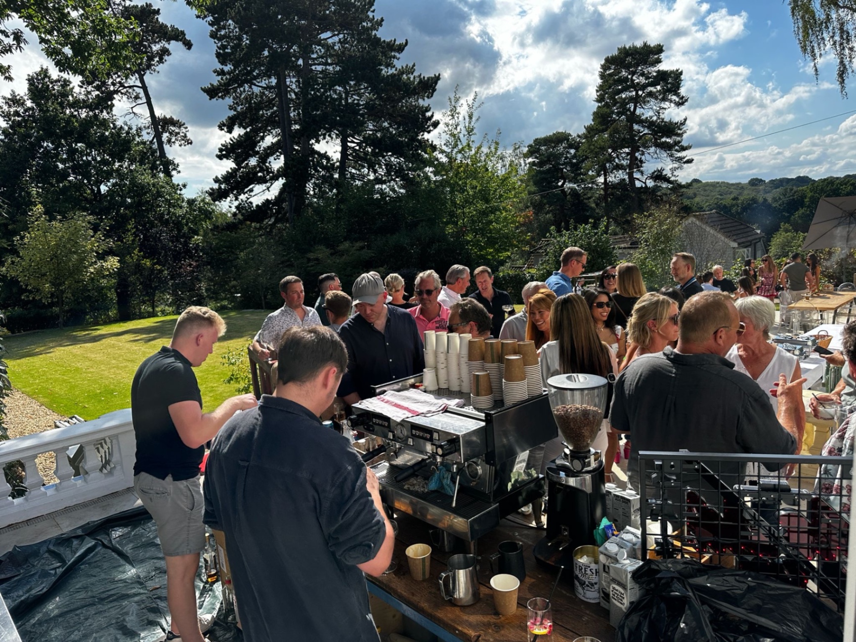 Guests gathered around the Fine Grind coffee bar on a sunlit terrace of a private mansion housewarming